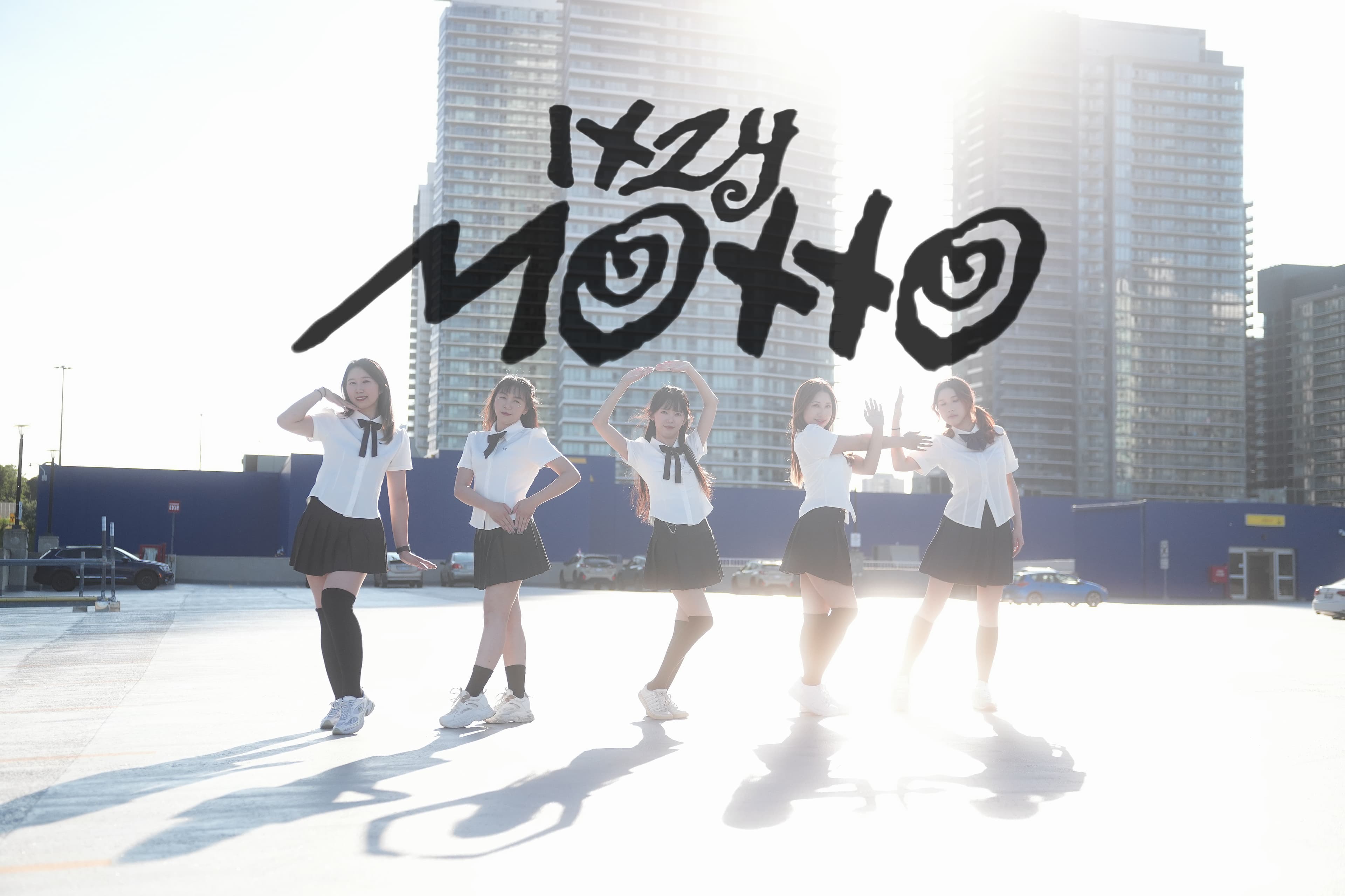 Five dancers in white shirts and black skirts posing in a sunlit parking lot in front of high-rise buildings for Motto by ITZY.