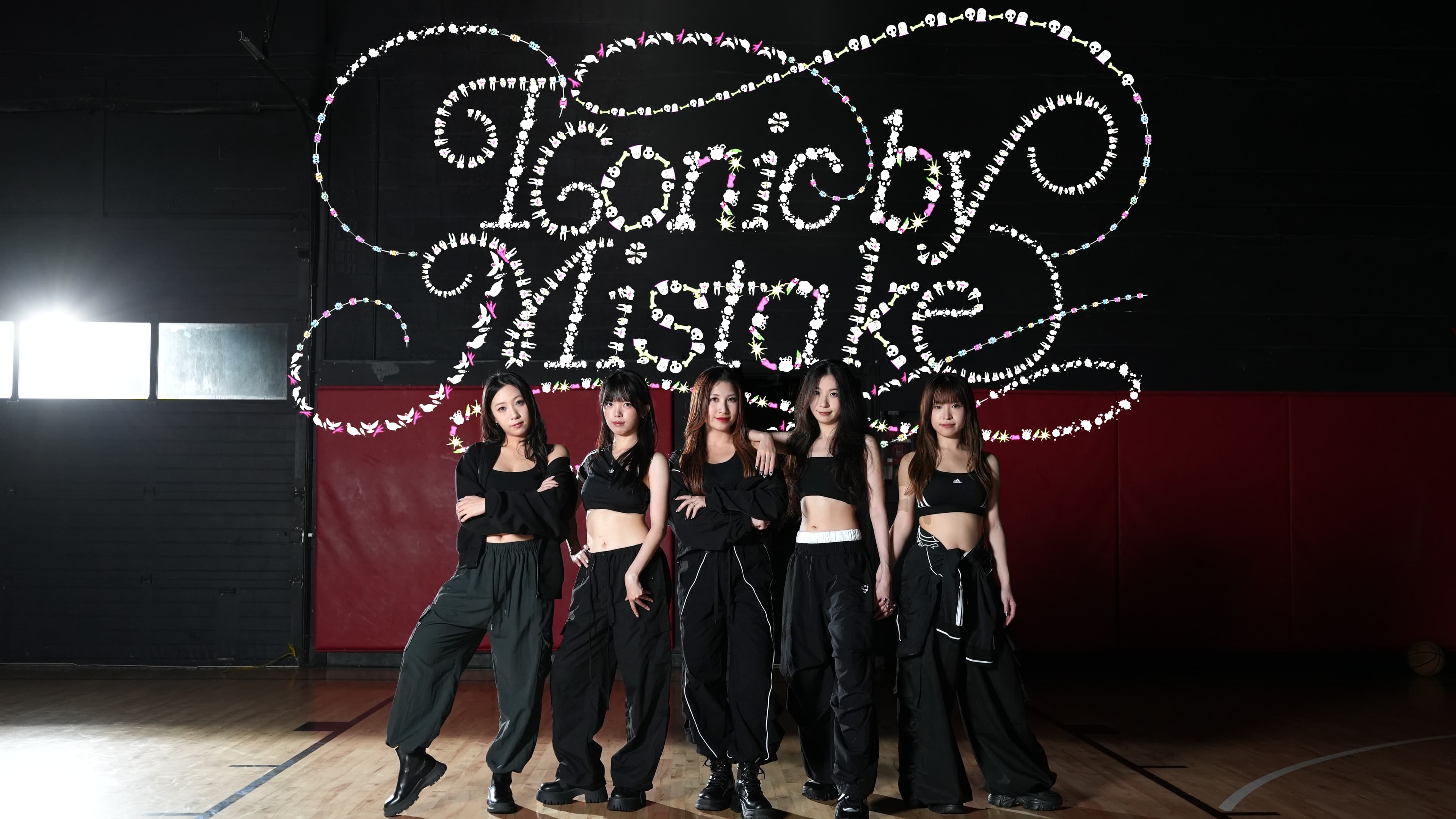 Five dancers in black outfits on a dark basketball court beneath the ICONIC BY MISTAKE title graphic.